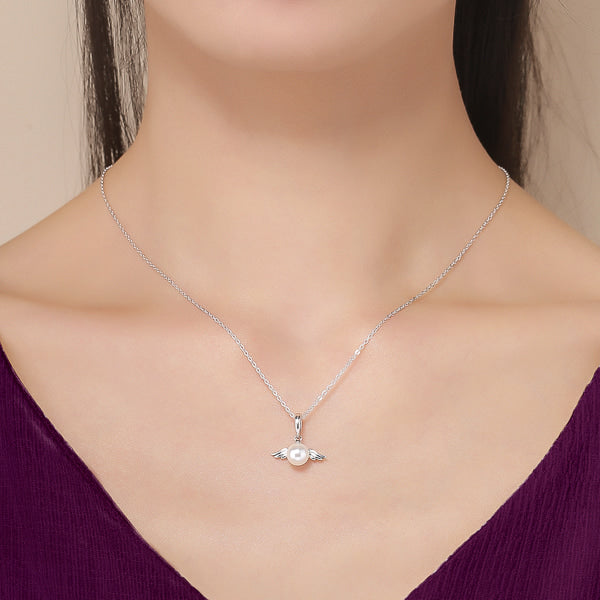 Silver necklace with a pendant displaying a pearl with angel wings shown on womans neck