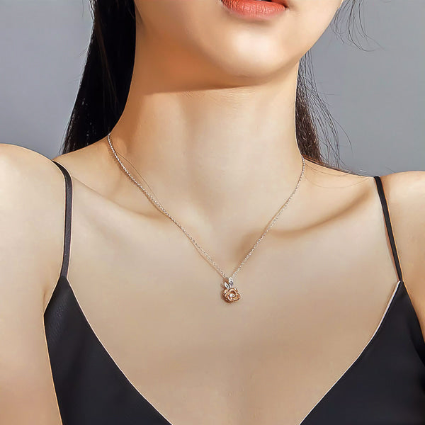 Silver necklace with a rose gold rose flower pendant on a woman's neck