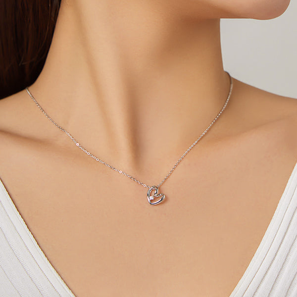 Woman wearing a silver silhouette heart and crystal pendant necklace