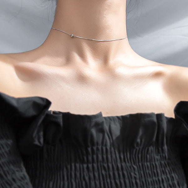 Woman wearing a silver single bead choker necklace