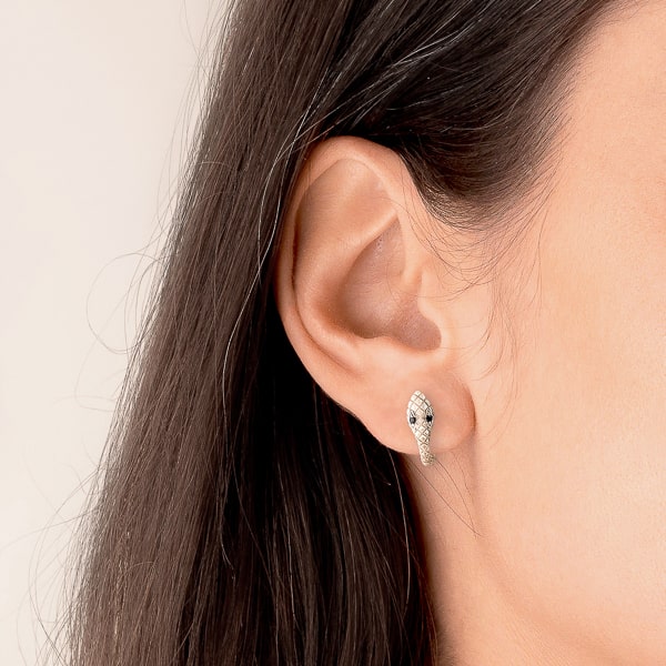 Woman wearing silver snake huggie hoop earrings