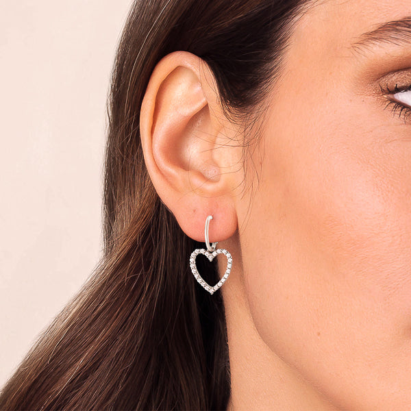 Woman wearing silver crystal heart dangle drop earrings