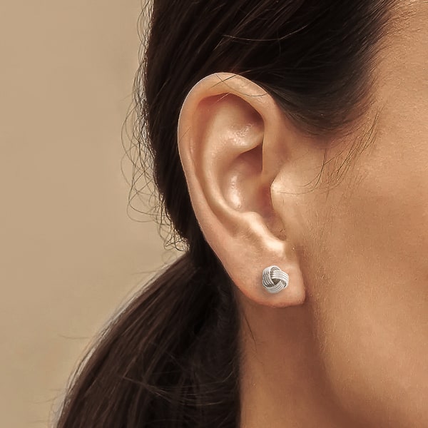 Woman wearing silver triple knot stud earrings
