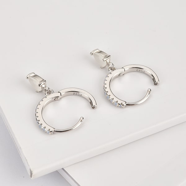 Details of silver huggie earrings with white crystal teardrops
