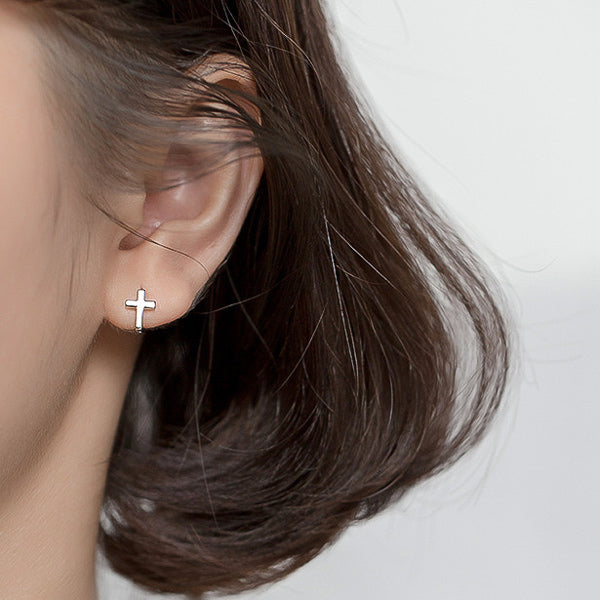 Woman wearing simple silver cross earrings