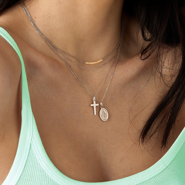 Woman wearing a simple silver cross pendant necklace