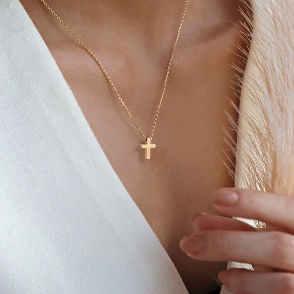 Woman wearing a small gold cross necklace