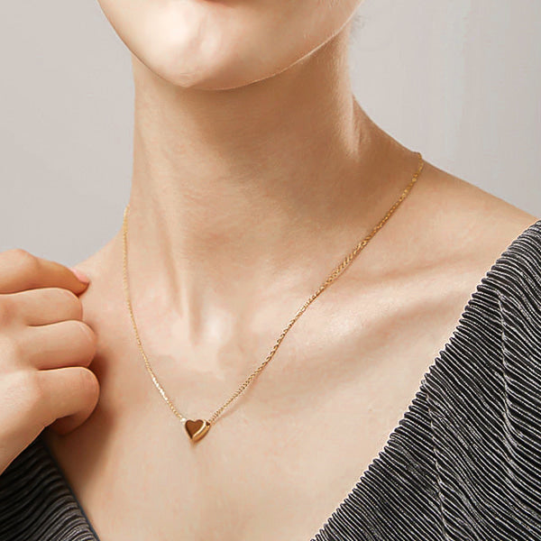 Woman wearing a small gold heart necklace