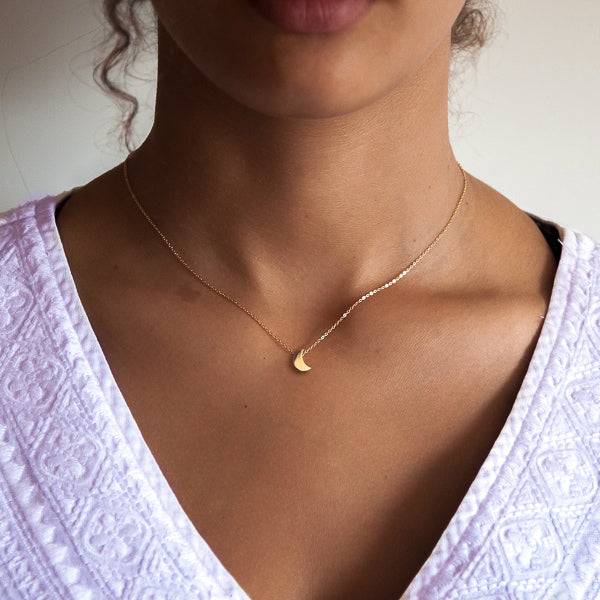 Woman wearing a small gold moon necklace