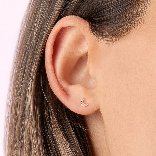Small rose gold moon stud earrings on woman