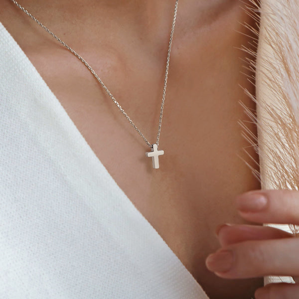 Woman wearing a small silver cross necklace
