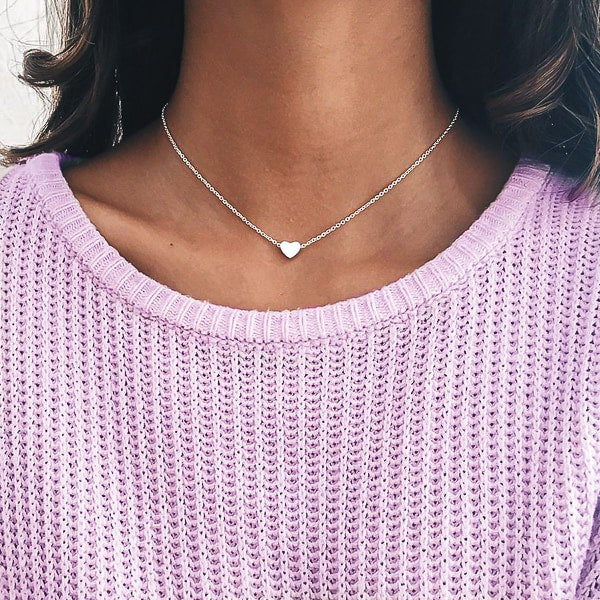 Woman wearing a small silver heart necklace