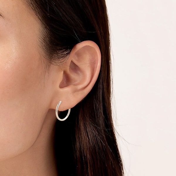Model wearing small thin silver hoop earrings