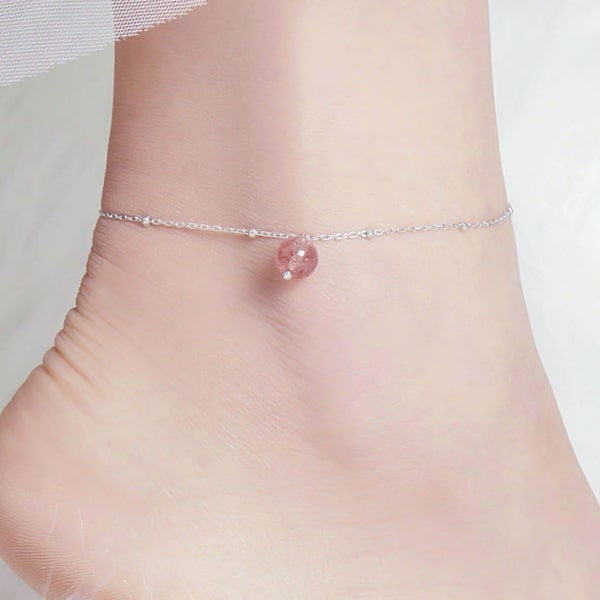 Sterling silver anklet with a red fire quartz crystal displayed on a womans ankle