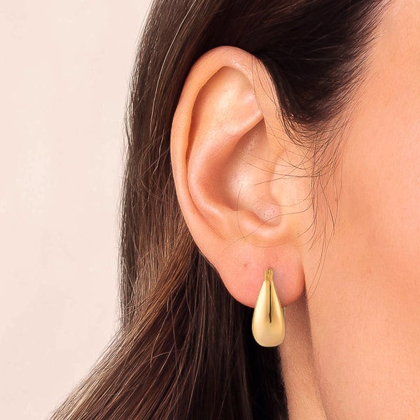 Woman wearing thick gold teardrop hoop earrings