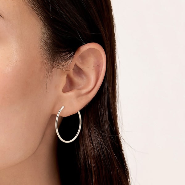 Model wearing thin silver hoop earrings