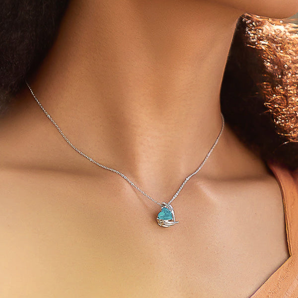 Woman wearing a turquoise crystal heart and angel wings pendant on a silver chain