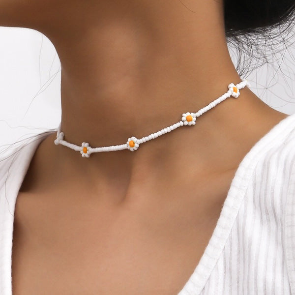 Woman wearing a white beaded daisy flower choker necklace