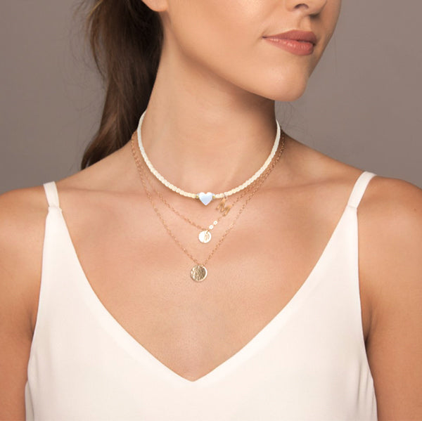 Woman wearing a white beaded initial letter choker necklace