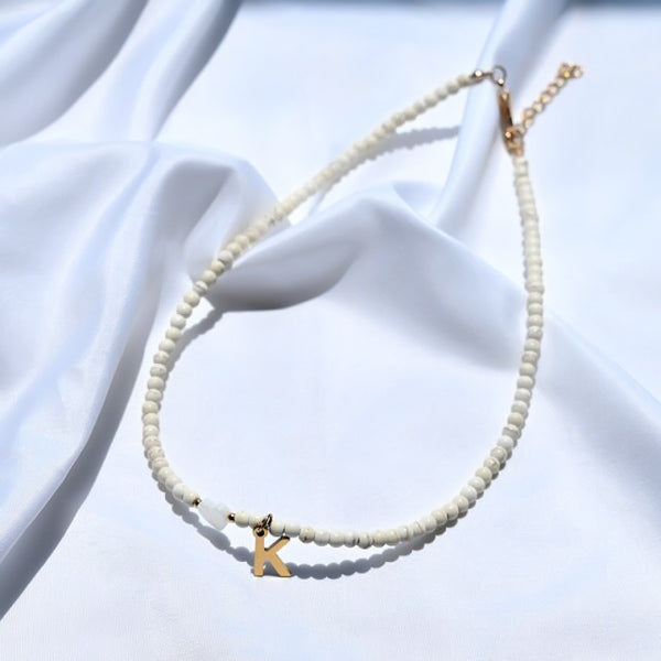 White beaded choker necklace with gold initial letter charm pendant