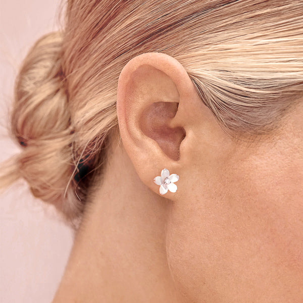 Woman wearing pearly white flower stud earrings