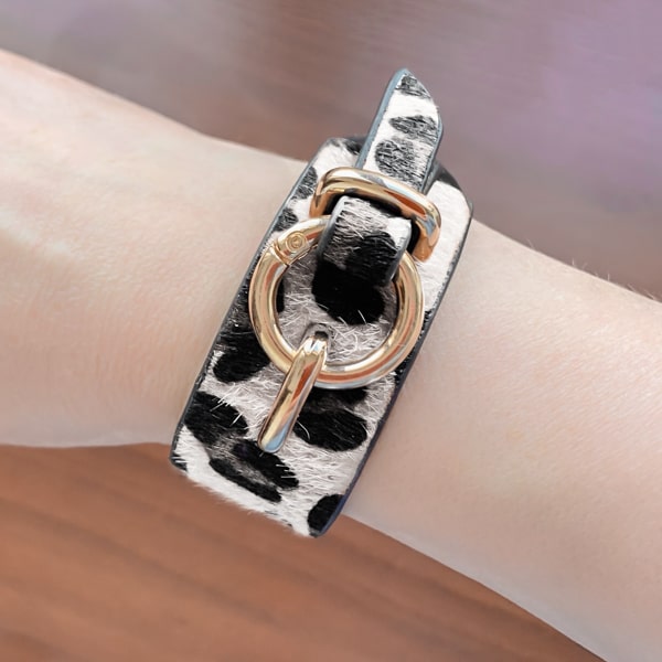 Woman wearing a white snow leopard bracelet with gold fashion clasp