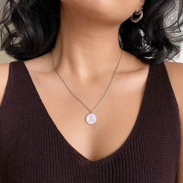 Woman wearing a silver and white round initial coin pendant necklace