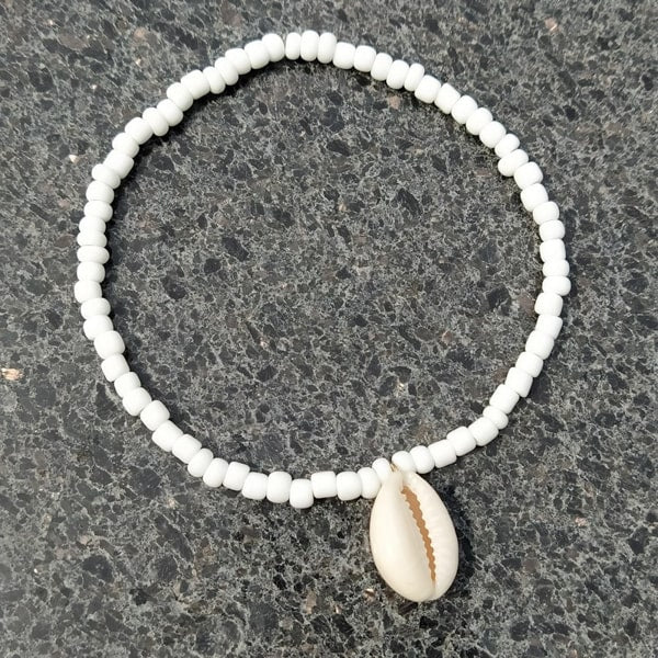 White beaded seashell anklet on a grey background