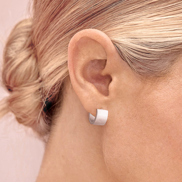 Woman wearing wide silver huggie hoop earrings